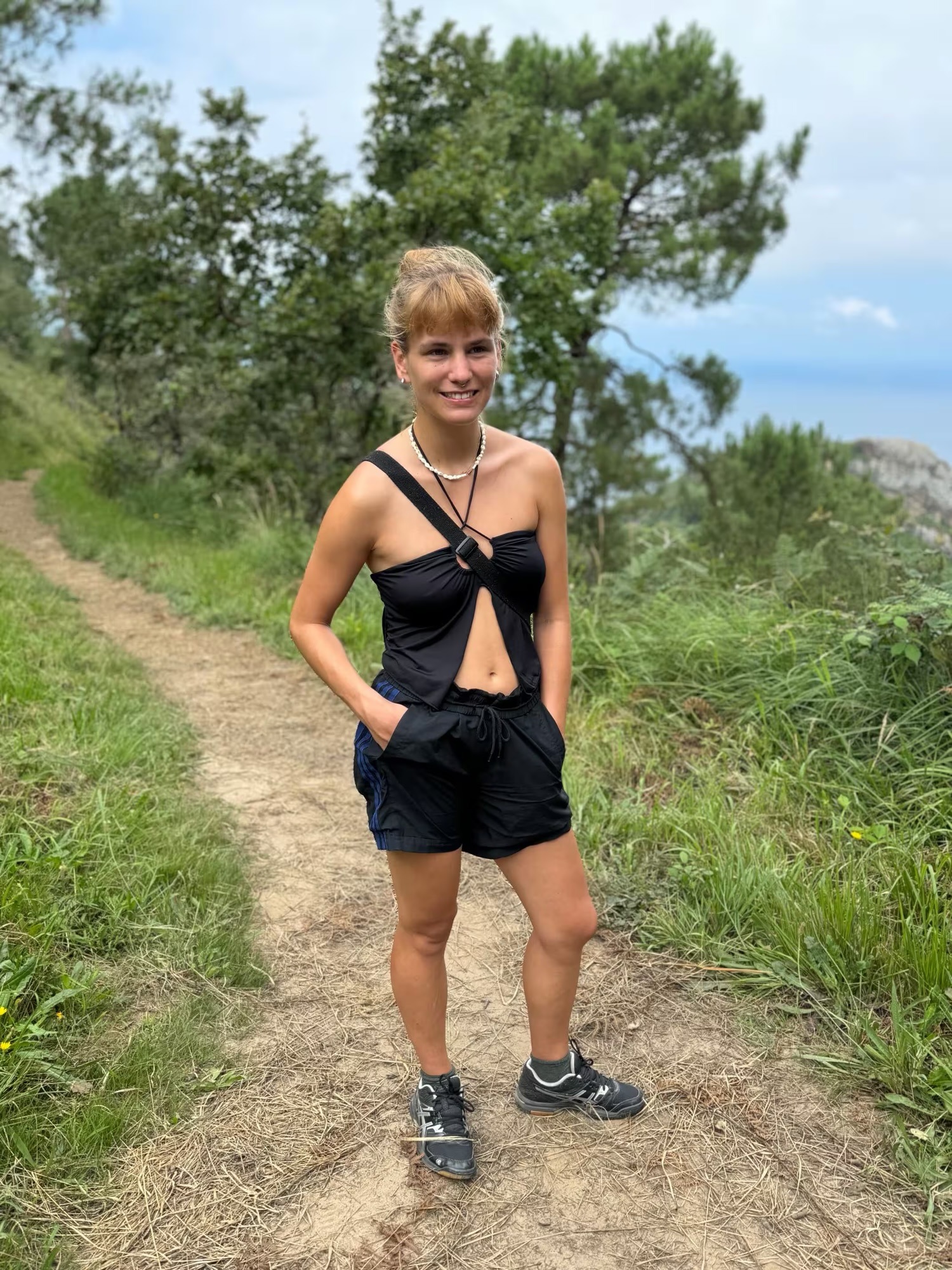 Wanderin auf einem Küstenpfad oberhalb von San Sebastián mit Blick auf das Kantabrische Meer