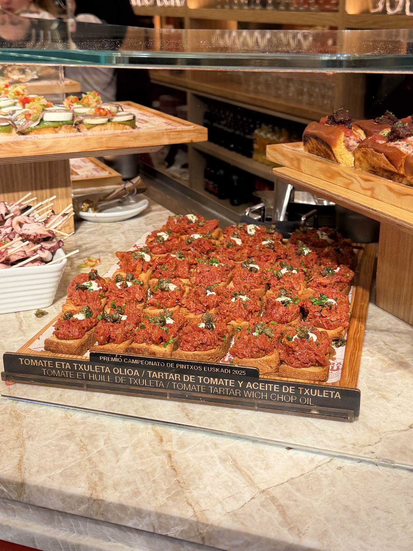 Mehrere Pintxos mit Tomate-Tartar und Txuleta-Öl auf einer Theke der Bar La Barra de Kojua in Donostia-San Sebastián.