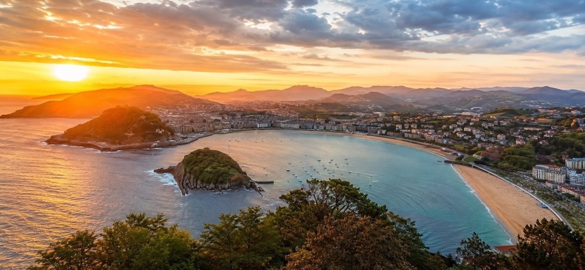 Panoramablick auf die Bucht La Concha in Donostia-San Sebastián bei Sonnenuntergang, mit Insel Santa Clara, Altstadt und Stränden