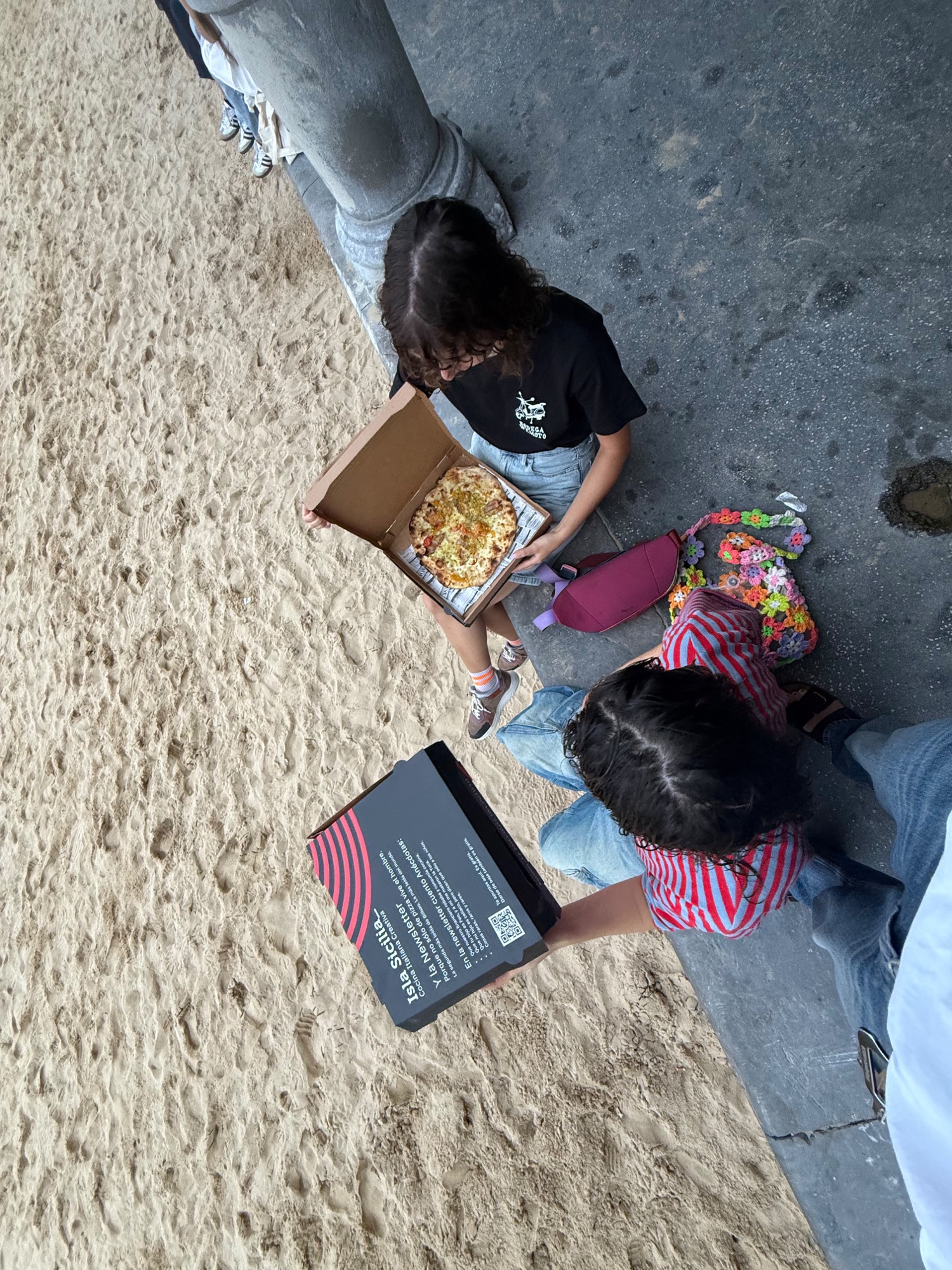 Zwei Damen genießen Pizza von Isla Sicilia an der Bucht La Concha in Donostia-San Sebastián.