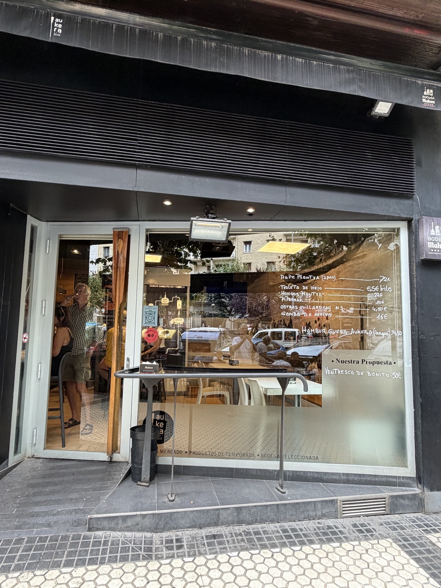 Eingangstür der Bar Aukera in Donostia-San Sebastián, die Tageskarte ist direkt auf die Glasfront geschrieben