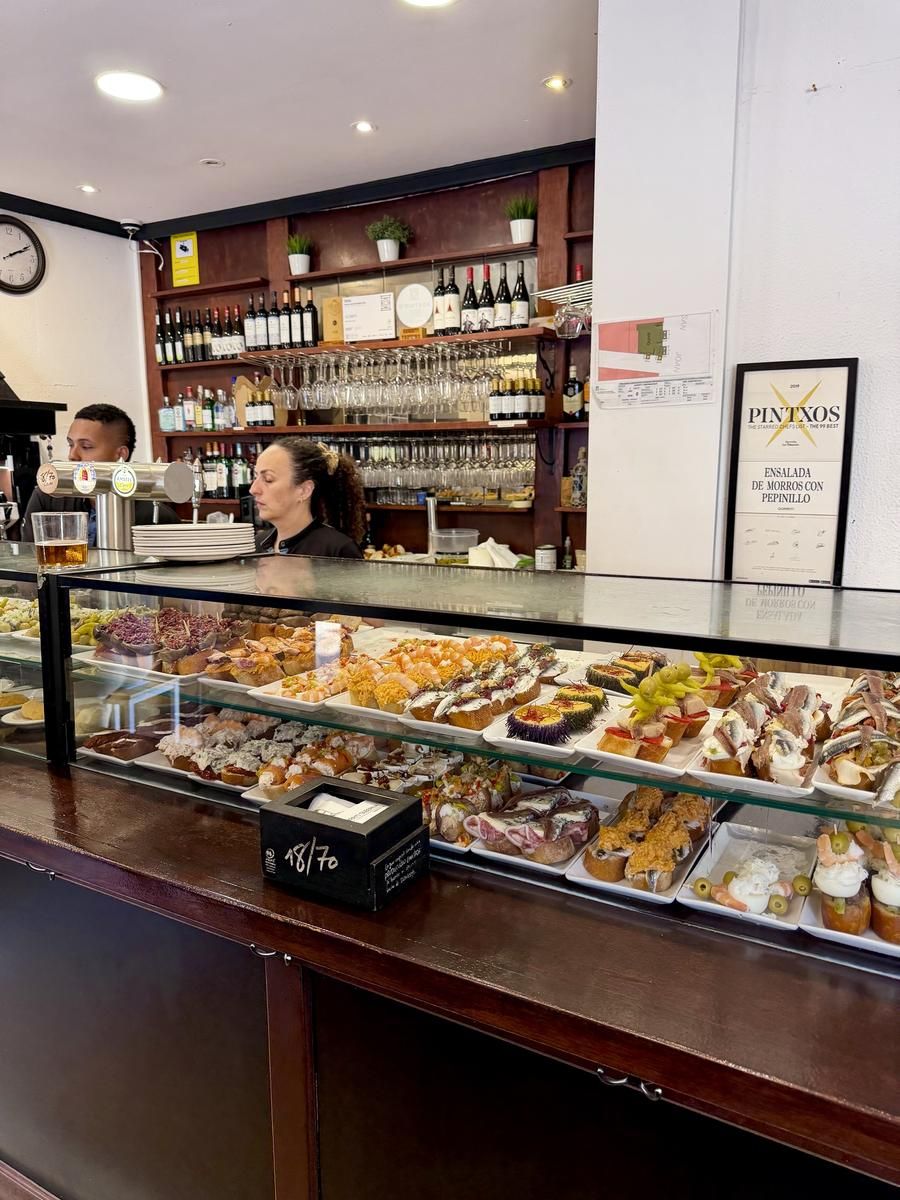 Gläserne Pintxo-Theke der Bar Gorriti in der Parte Vieja von Donostia-San Sebastián mit Anchoas, Seeigel, Gildas und Brochetas, dahinter Weinregal und die gerahmte Auszeichnung für die Ensalada de morros